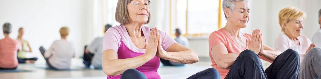Elderly women meditating during yoga in a senior living community