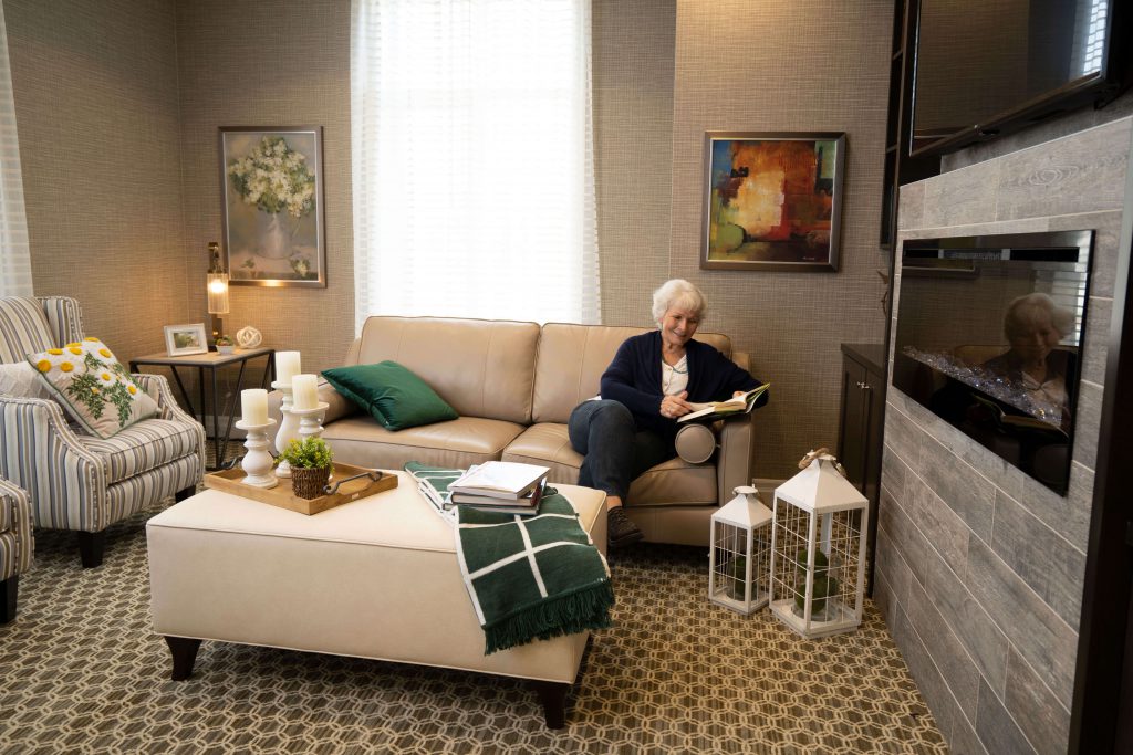 Resident reading a book while sitting in a Seasons home lounge area