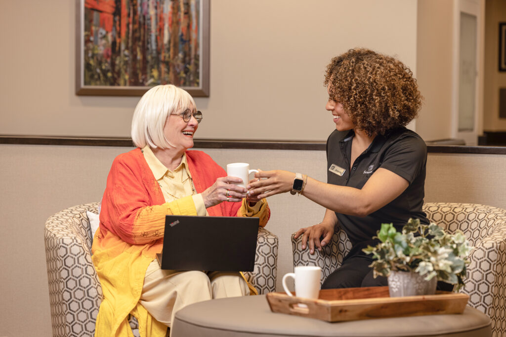 Seasons Team Member Passing Over A Mug to a Resident While Seated