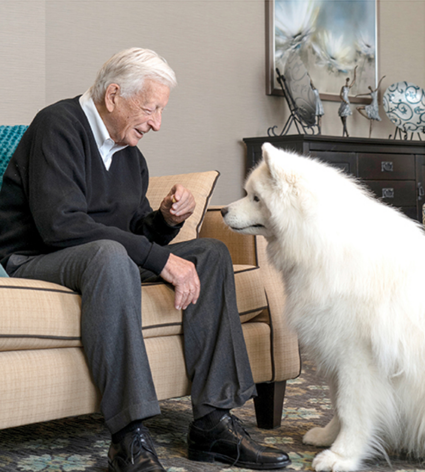 Senior man accompanied by white dog in senior living apartments