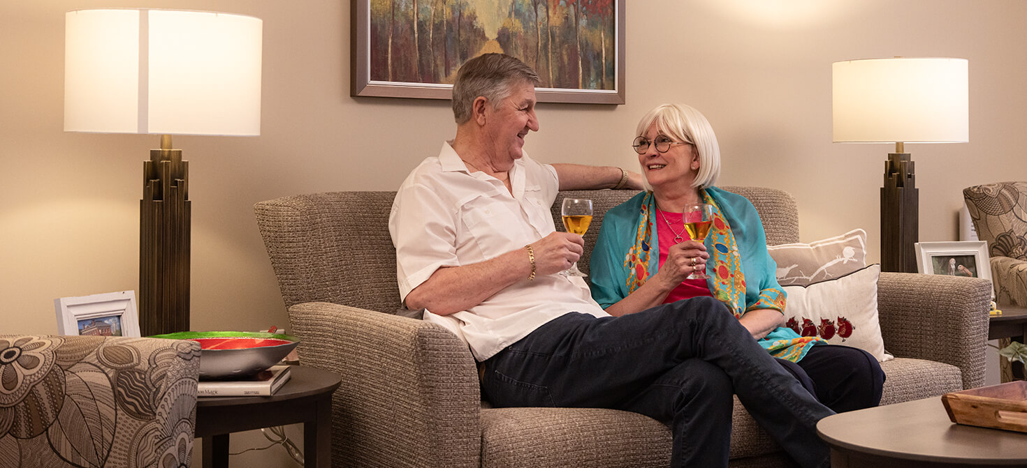 Elderly couple enjoying a glass of wine in their suite at Seasons Retirement