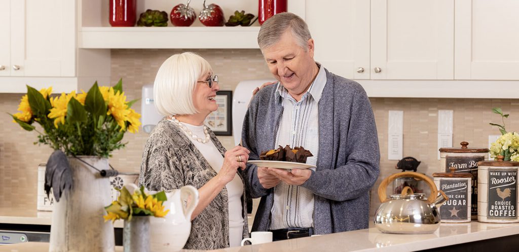 Two seniors sharing a plate of muffins in senior living apartments