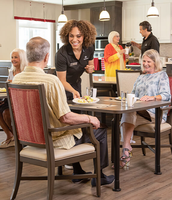 Careworker serving food to residents of the retirement community at a table