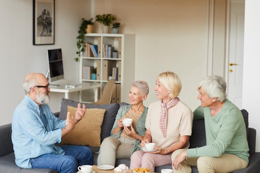 A group of cheerful seniors enjoying a friendly conversation over coffee in a warm, inviting living room.