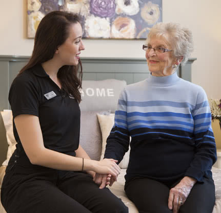 A seasons staff member holding a resident's hand