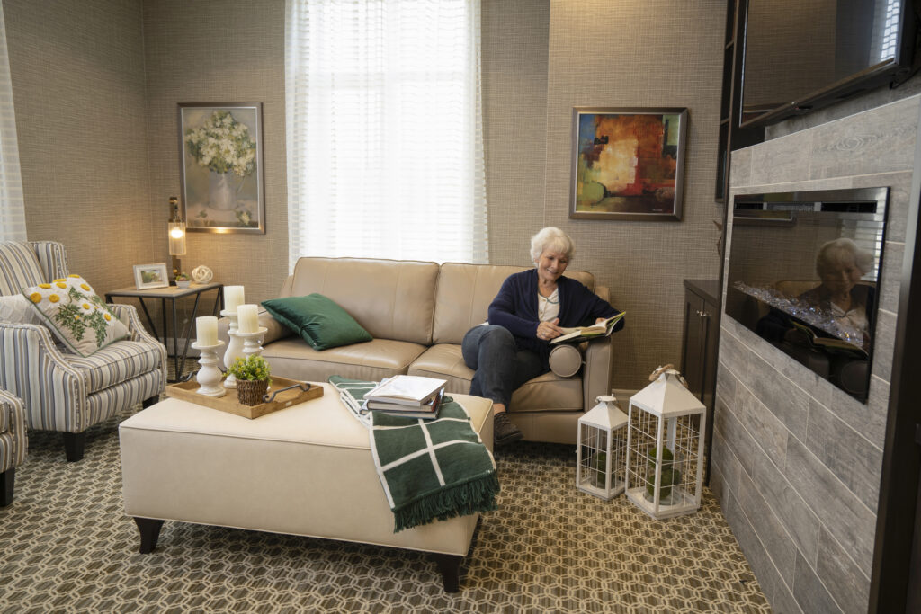 Resident reading a book while sitting in a Seasons home lounge area