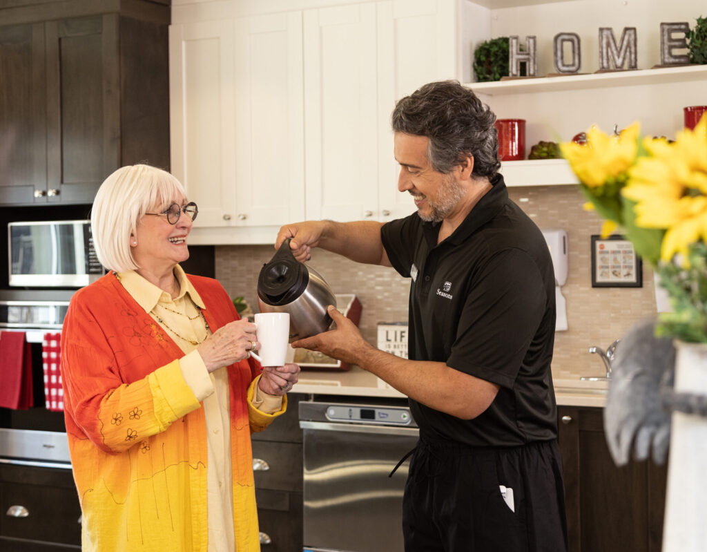 Seasons Team Member Pouring Coffee for a Smiling Resident in Common Area