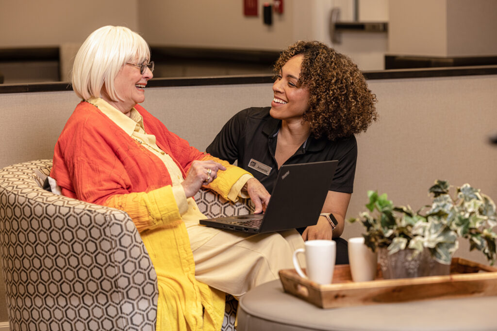 Seasons Team Member Laughing With Resident While Seated