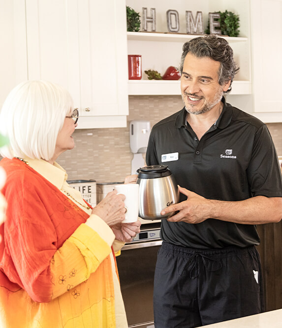 Male caregiver pouring coffee for elderly woman