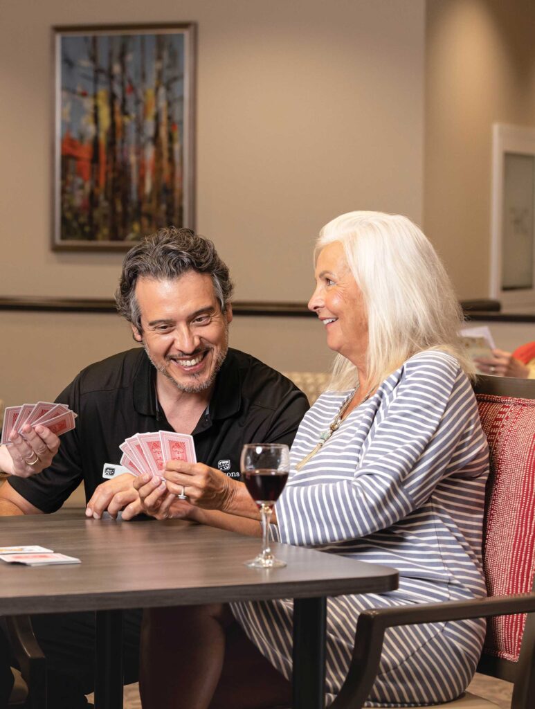 Seasons retirement team member playing cards with senior woman