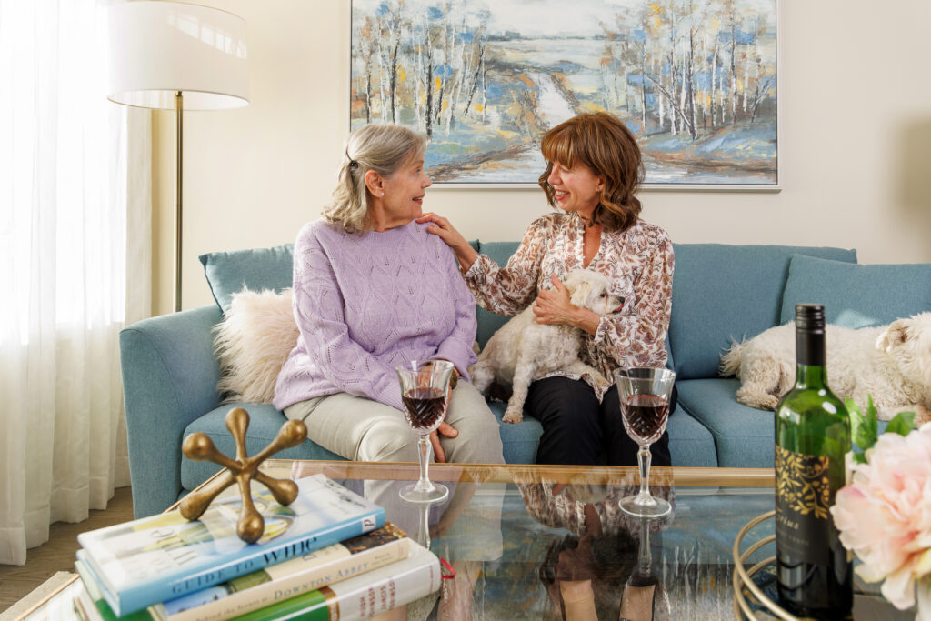 Two ladies sitting on a couch side by side enjoying a conversation together.